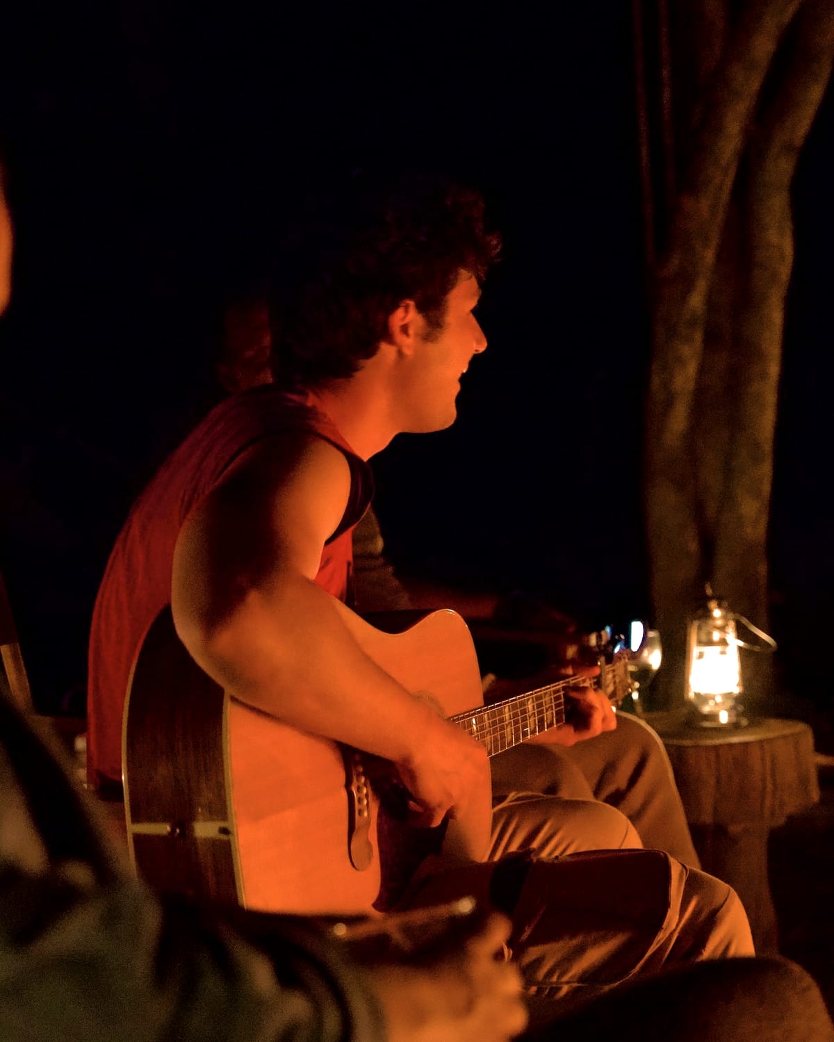 Guitare à la lueur d’une lanterne, autour du feu
